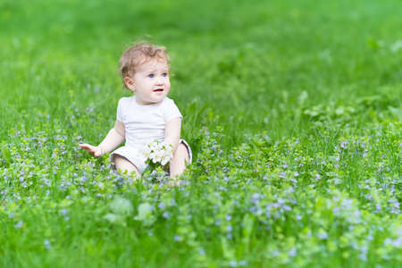 Beautiful little girl playing with flowers の写真素材