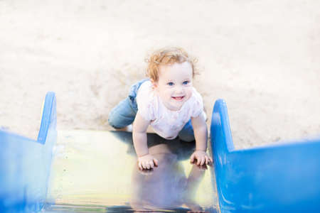 Laughing baby girl playing on a slide 