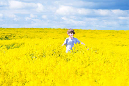 Happy laughing child running in a field of yellow flowers 