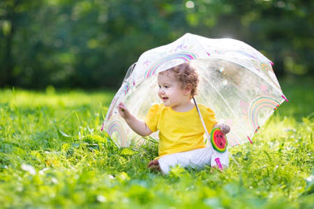 Cute little baby girl playing in the garden under an umbrella on の写真素材