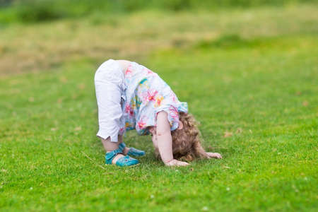 Adorable funny baby girl standing with her head down in a summer 