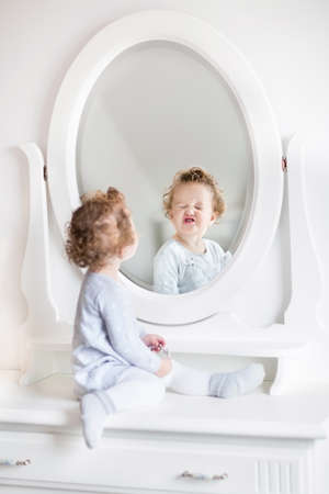 Very Funny Baby Girl With Curly Hair Looking At Her Reflection In