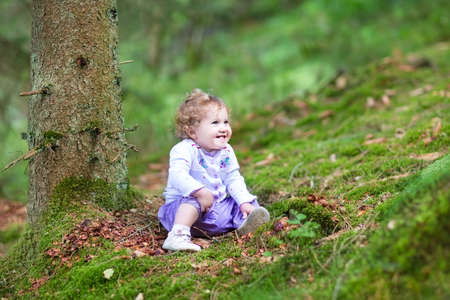 Happy laughing baby girl playing in a beautiful pine wood forest in autumn の写真素材