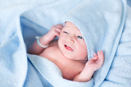 Funny newborn baby covered n a blue bath towel の写真素材