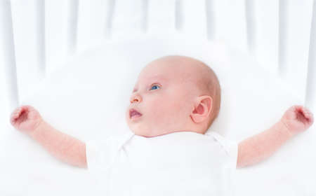 Sweet newborn baby in a white round crib の写真素材