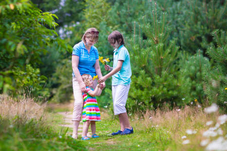 Happy active woman enjoying hiking with two children, school age boy and cute curly toddler girl...