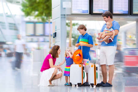 Big happy family with three kids travelling by airplane at Dusseldorf International airport, parents with teenager boy, toddler girl and little baby holding colorful luggage for summer beach vacationの写真素材