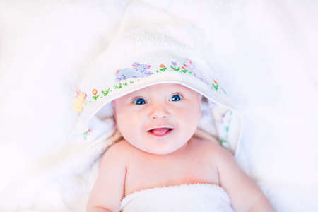 Cute laughing baby in a hand made cross stitch hooded towel  の写真素材