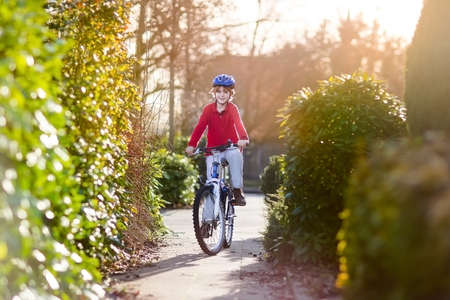 Happy smiling teenager boy riding his bike on sunset  の写真素材