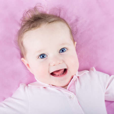 Portrait of a beautiful baby girl on pink backgroundの写真素材