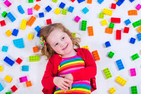 Child playing with colorful toys. Little girl with educational toy blocks. Children play at day care or preschool. Mess in kids room. View from above.の写真素材