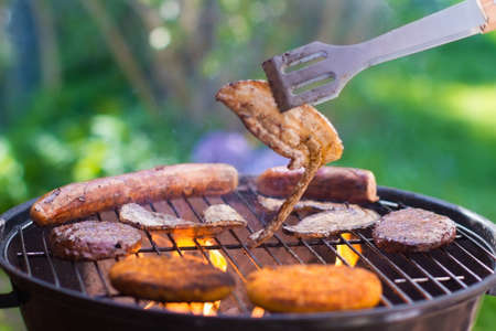 Grilled meat on bbq. Barbecue lunch in the garden. Grill tools. German sausage and steak for outdoor dinner.の写真素材
