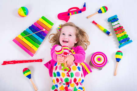 Child with music instruments. Musical education for kids. Colorful wooden art toys for kids. Little girl playing music. Kid with xylophone, guitar, flute.の写真素材