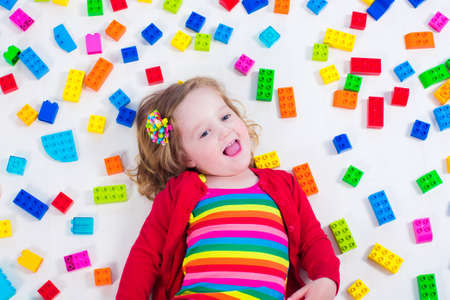 Child playing with colorful toys. Little girl with educational toy blocks. Children play at day care or preschool. Mess in kids room. View from above.の写真素材
