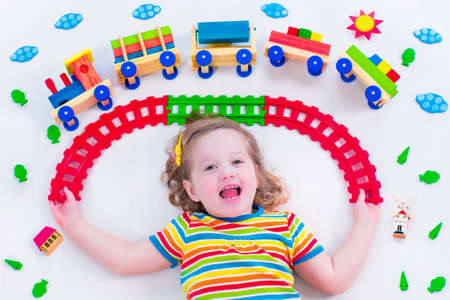 Child playing with wooden train. Toy railroad for kids. Toddler kid at day care. Educational toys...