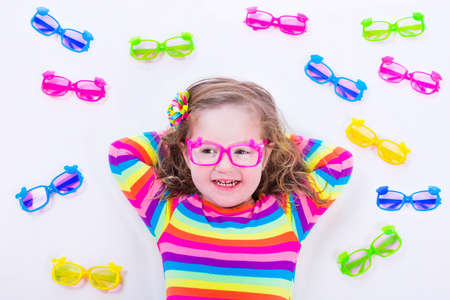 Child wearing eye glasses. Eye wear for kids. Little girl choosing spectacles. Lens and colorful...