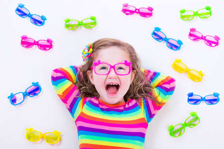 Child wearing eye glasses. Eye wear for kids. Little girl choosing spectacles. Lens and colorful frame choice for children. Vision and sight control at optician shop. Smart preschooler with eyeglassesの写真素材