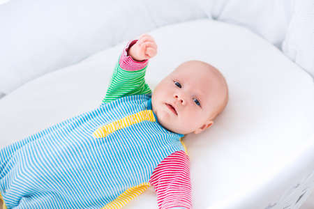 Newborn baby boy playing in bed on a sunny morning. New born child relaxing in bassinet. Children...