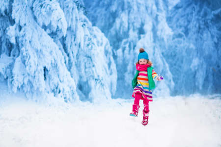 Little girl enjoying a sleigh ride. Child sledding. Toddler kid riding a sledge. Children play outdoors in snow. Kids sled in the Alps mountains in winter. Outdoor fun for family Christmas vacation.の写真素材