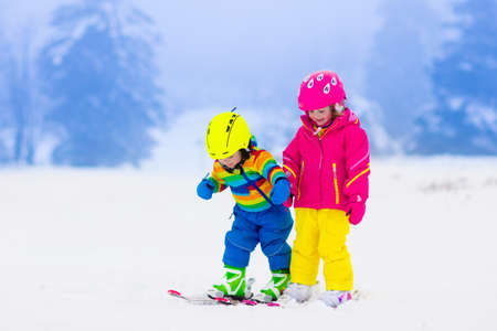 Children skiing in the mountains. Toddler kids in colorful suit and safety helmet learning to ski. Winter sport for family with young child. Kid ski lesson in alpine school. Snow fun for little skier.の写真素材