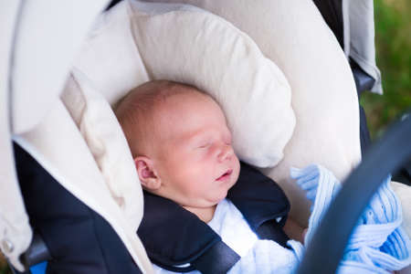 Newborn baby boy sleeping in modern car seat. New born child traveling by car. Child safety on the road. Safe way to travel with young kids. Fastened seat belts in a vehicle. Trip with an infant.の写真素材