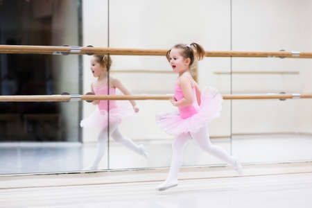 Little ballerina girl in a pink tutu. Adorable child dancing classical ballet in a white studio. Children dance. Kids performing. Young gifted dancer in a class. Preschool kid taking art lessons.の写真素材