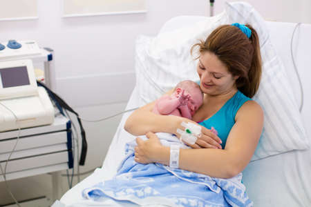 Mother giving birth to a baby. Newborn baby in delivery room. Mom holding her new born child after labor. Female pregnant patient in a modern hospital. Parent and infant first moments of bonding. Mother giving birth to a baby. Newborn baby in delivery room. Mom holding her new born child after labor. Female pregnant patient in a modern hospital. Parent and infant first moments of bonding.