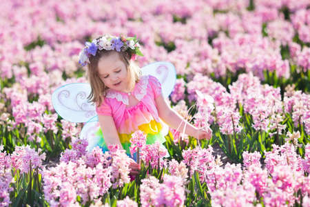 Beautiful girl playing in blooming hyacinth flower field. Kids princess birthday party with fairy...