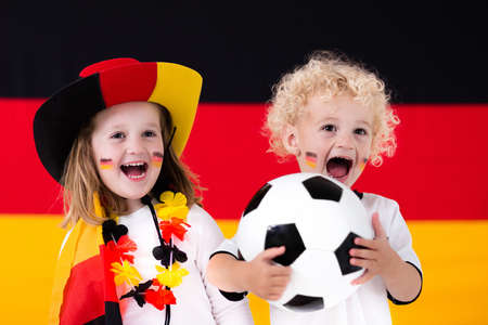 Children cheering and supporting German national football team. Kids fans and supporters of Germany during soccer championship.の写真素材