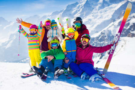 Family ski vacation. Group of skiers in Swiss Alps mountains. Adults and young children, teenager and baby skiing in winter. Parents teach kids alpine downhill skiing. Ski gear and wear, safe helmets.の写真素材