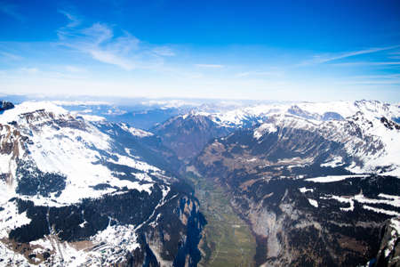 Aerial view of the Alps mountains in Switzerland. View from helicopter above glacier in Swiss Alps. Mountain tops covered in snow. Alpine ski facilities from above.の写真素材