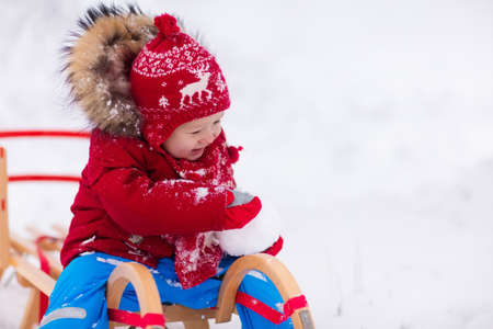 Little girl enjoying a sleigh ride. Child sledding. Toddler kid riding a sledge. Children play outdoors in snow. Kids sled in the Alps mountains in winter. Outdoor fun for family Christmas vacation.の写真素材