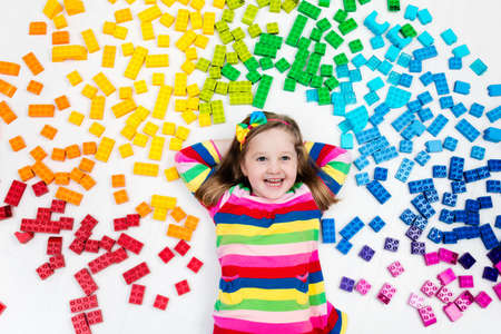 funny little girl playing with colorful rainbow plastic blocks kids play create and learn colors educational toys for creative children preschooler building block toys kid playing on the floorの写真素材