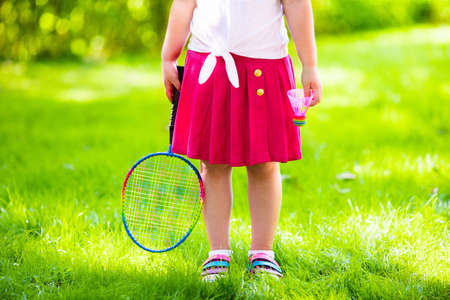 Active preschool girl playing badminton in outdoor court in summer. Kids play tennis. School sports for children. Racquet and shuttlecock sport for child athlete. Kid with racket and shuttle.の写真素材
