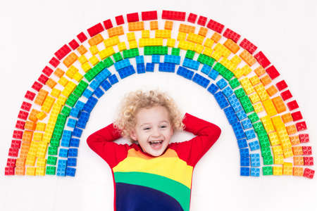 Funny little boy playing with colorful rainbow plastic blocks. Kids play, create and learn colors. Educational toys for creative children. Preschooler building block toys. Kid playing on the floor.の写真素材