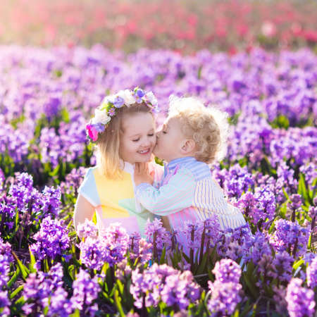 Kids gardening. Children play outdoors in hyacinths meadow. Little girl and boy, brother and sister, work in the garden, planting hyacinth flowers, watering hyacinth flower bed. Family fun in summer.の写真素材