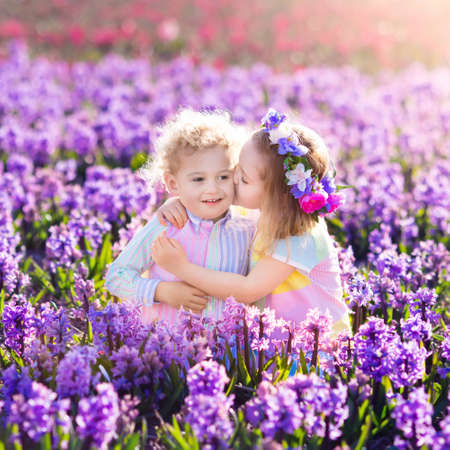 Kids gardening. Children play outdoors in hyacinths meadow. Little girl and boy, brother and sister, work in the garden, planting hyacinth flowers, watering hyacinth flower bed. Family fun in summer.の写真素材