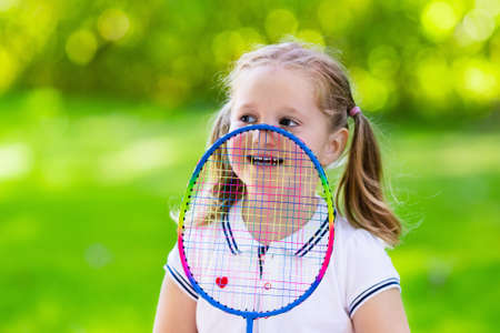 Active preschool girl playing badminton in outdoor court in summer. Kids play tennis. School sports for children. Racquet and shuttlecock sport for child athlete. Kid with racket and shuttle.の写真素材