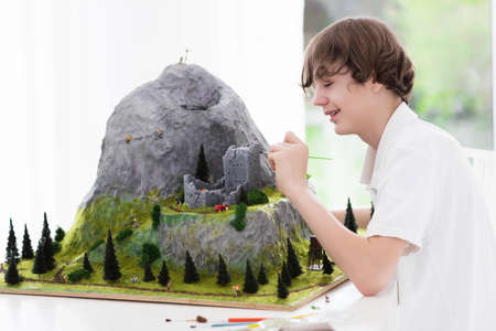 Teenager working on model building school project. Kids build miniature scale model mountain for geography class in high school. Extracurricular activities and hobby club. Art and crafts for child.の写真素材