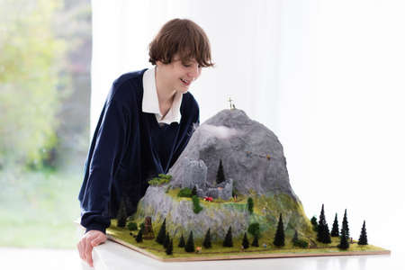 Teenager working on model building school project. Kids build miniature scale model mountain for geography class in high school. Extracurricular activities and hobby club. Art and crafts for child.の写真素材