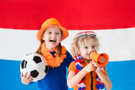 Children cheering and supporting Dutch football team. Kids fans and supporters of the Netherlands during soccer championship. Boy and girl from Holland with national flag and country symbols.の写真素材