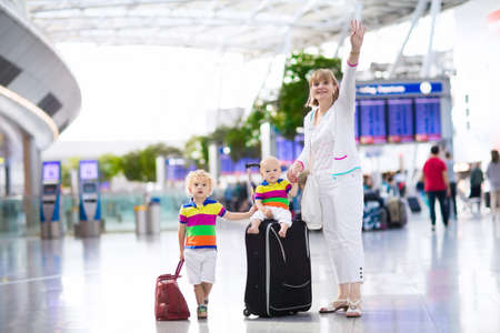 Family at airport before flight. Mother and kids waiting to board at departure gate of modern international terminal. Traveling and flying with children. Mom with baby and toddler boarding airplane.の写真素材