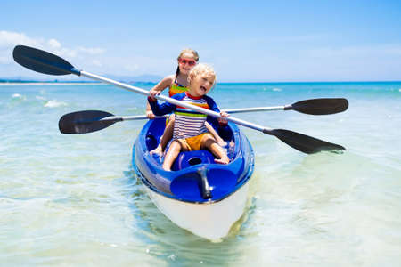 Kids kayaking in ocean. Children in kayak in tropical sea. Active vacation with young kid. Boy and girl in canoe on beautiful beach. Holiday activity with preschool child. Family water fun.の写真素材