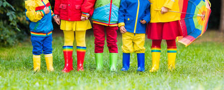 Kids in rain boots. Group of kindergarten children in colorful rubber boots and autumn jackets. Footwear for rainy fall. Foot wear for child and baby. Toddler in wellies. Rainbow gumboots. Kid fashionの写真素材