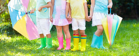 Kids in rain boots. Group of kindergarten children in colorful rubber boots and autumn jackets. Footwear for rainy fall. Foot wear for child and baby. Toddler in wellies. Rainbow gumboots. Kid fashionの写真素材