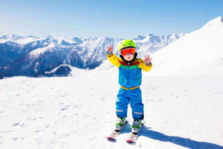 Child skiing in the mountains. Kid in ski school. Winter sport for kids. Family Christmas vacation in the Alps. Children learn downhill skiing. Alpine ski lesson for boy or girl. Outdoor snow fun.の写真素材