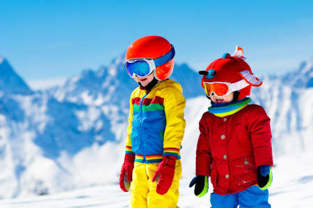 Child skiing in the mountains. Kid in ski school. Winter sport for kids. Family Christmas vacation in the Alps. Children learn downhill skiing. Alpine ski lesson for boy and girl. Outdoor snow fun.の写真素材