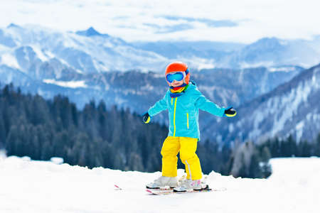 Child skiing in the mountains. Kid in ski school. Winter sport for kids. Family Christmas vacation in the Alps. Children learn downhill skiing. Alpine ski lesson for boy or girl. Outdoor snow fun.の写真素材