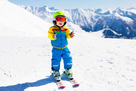 Child skiing in the mountains. Kid in ski school. Winter sport for kids. Family Christmas vacation in the Alps. Children learn downhill skiing. Alpine ski lesson for boy or girl. Outdoor snow fun.の写真素材