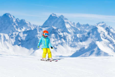 Child skiing in the mountains. Kid in ski school. Winter sport for kids. Family Christmas vacation in the Alps. Children learn downhill skiing. Alpine ski lesson for boy or girl. Outdoor snow fun.の写真素材
